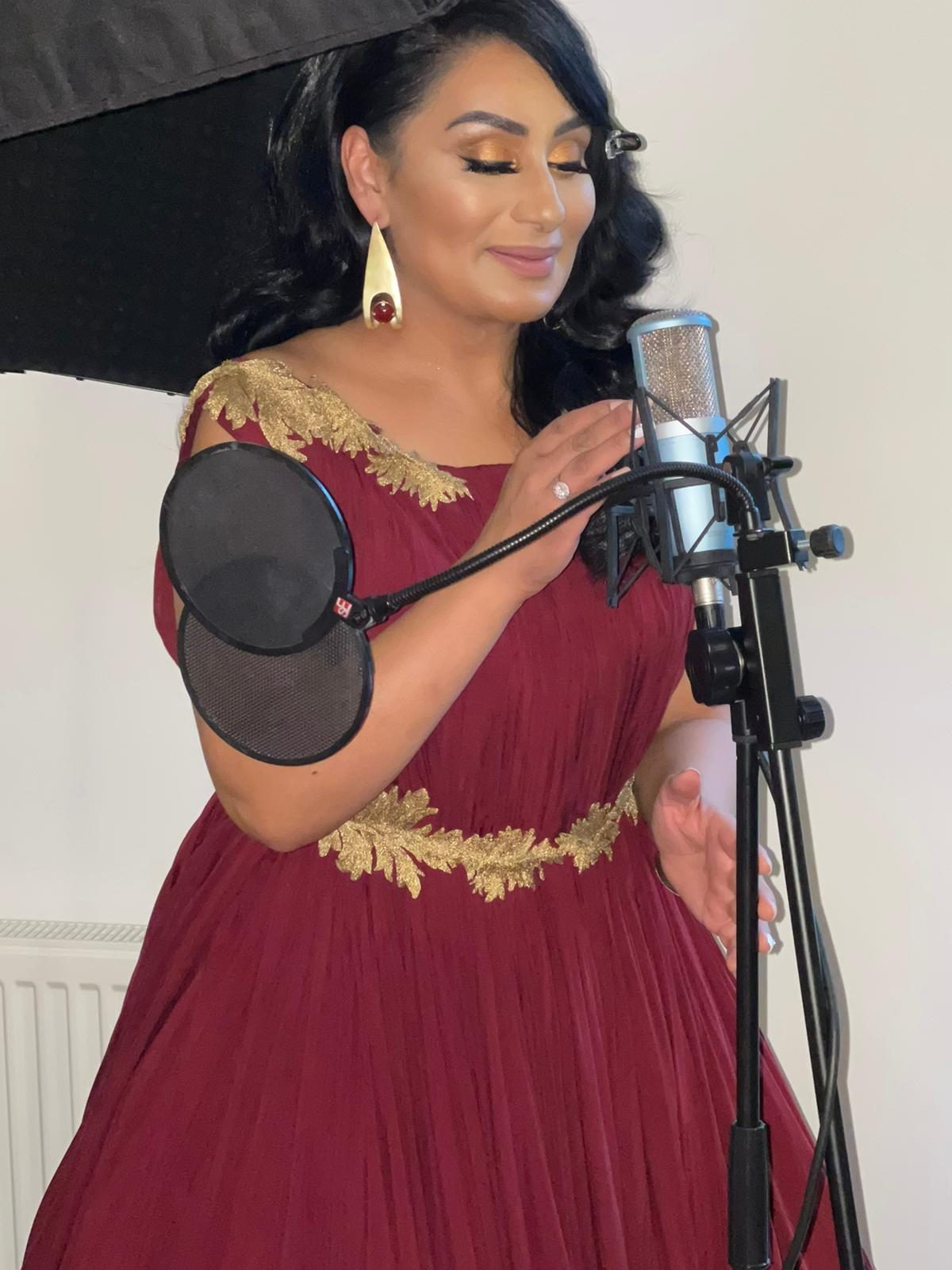 Reena Kaur recording vocals at a studio microphone
