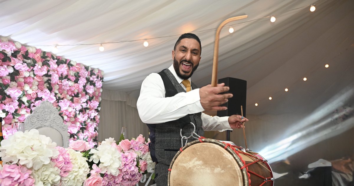 Dhol player performing at a marquee wedding reception