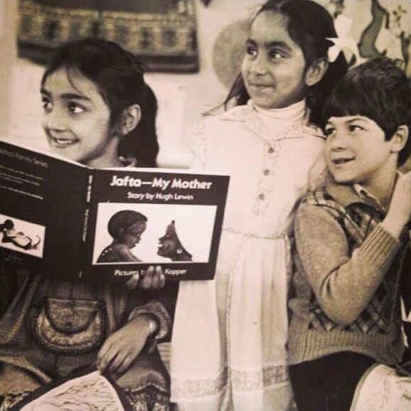 Black-and-white school photograph of three young children, one holding open a picture book