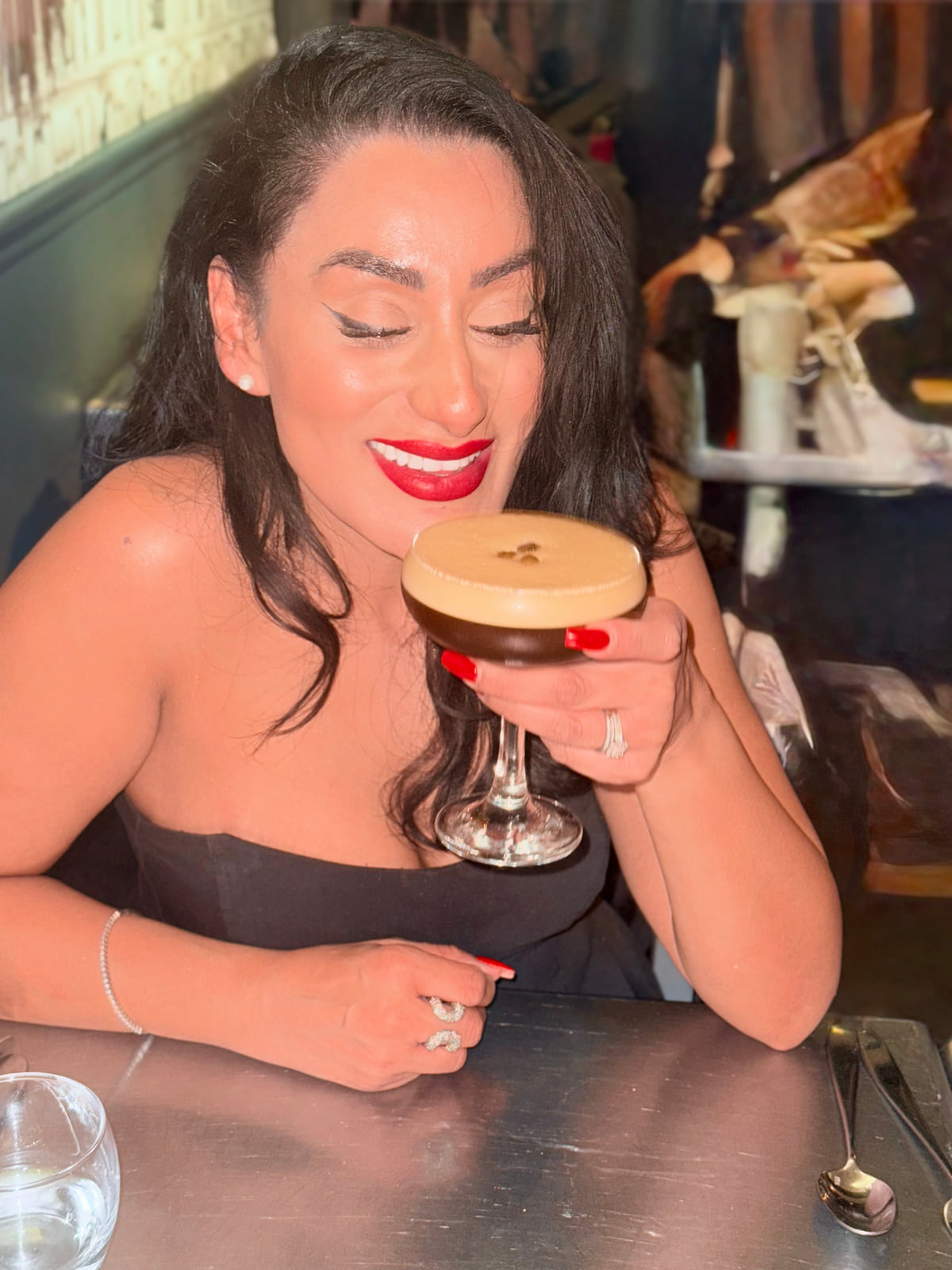 Reena Kaur smiling with an espresso martini at a restaurant table